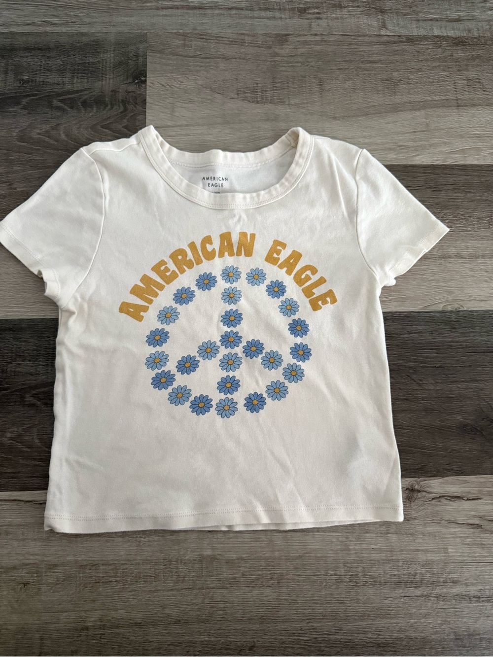 American Eagle Outfitters White Tee with Yellow Logo and Blue Floral Peace Sign
